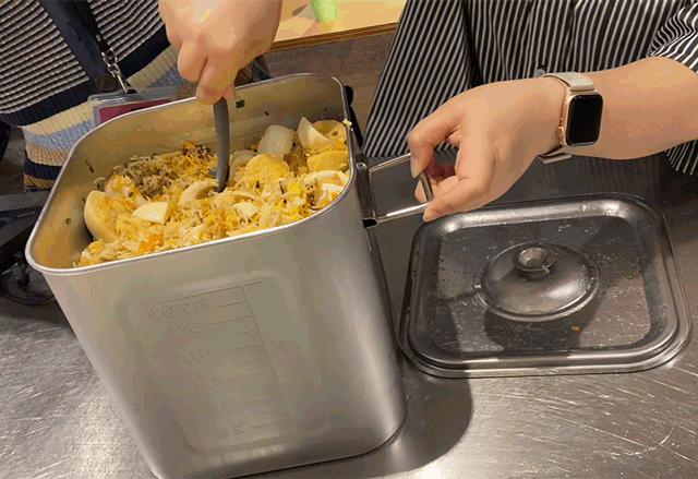 写真:一斗缶ビリヤニに大きなレードルをいれて混ぜている